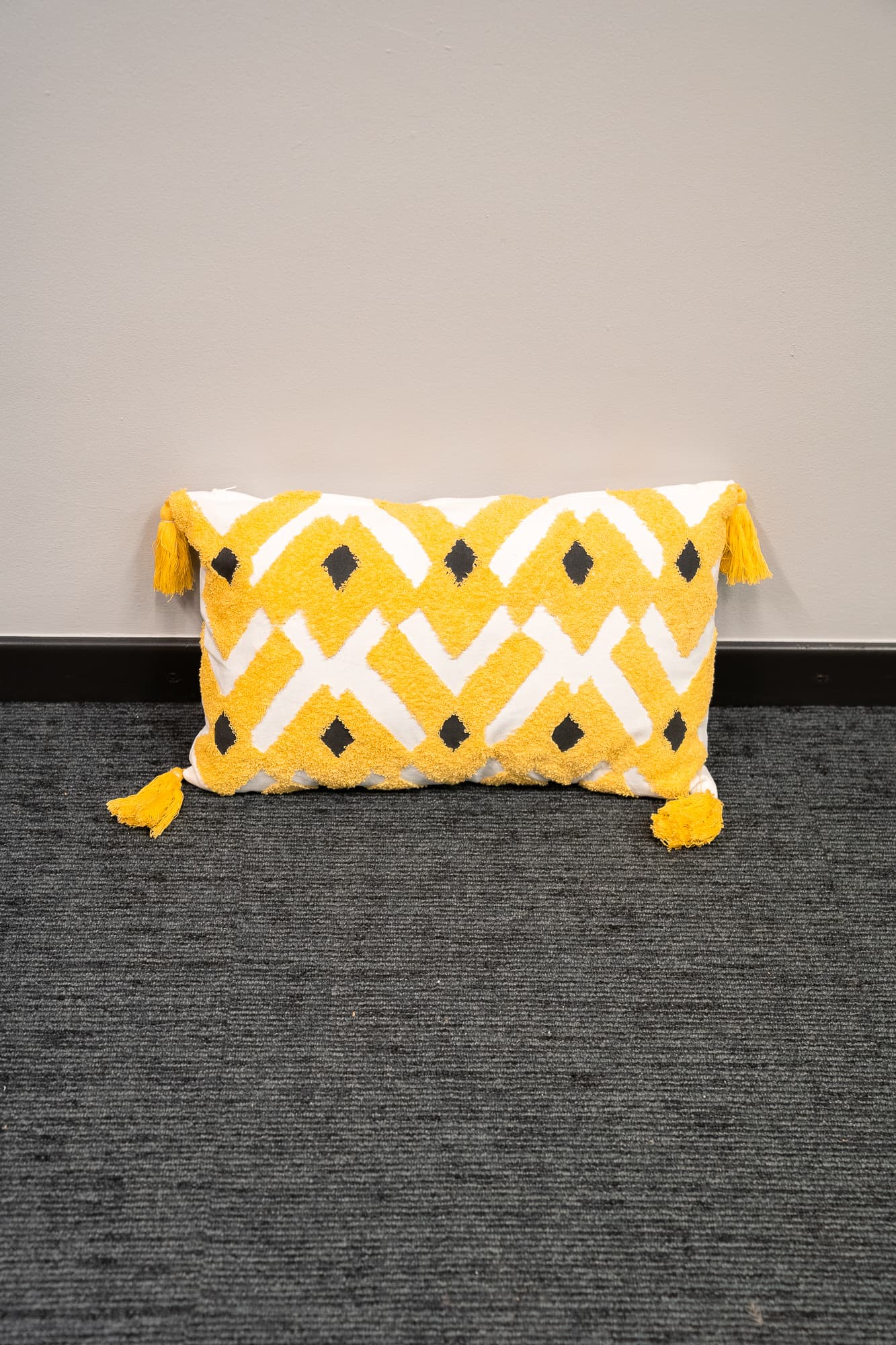 white rectangular cushion with yellow embroidery and tassels