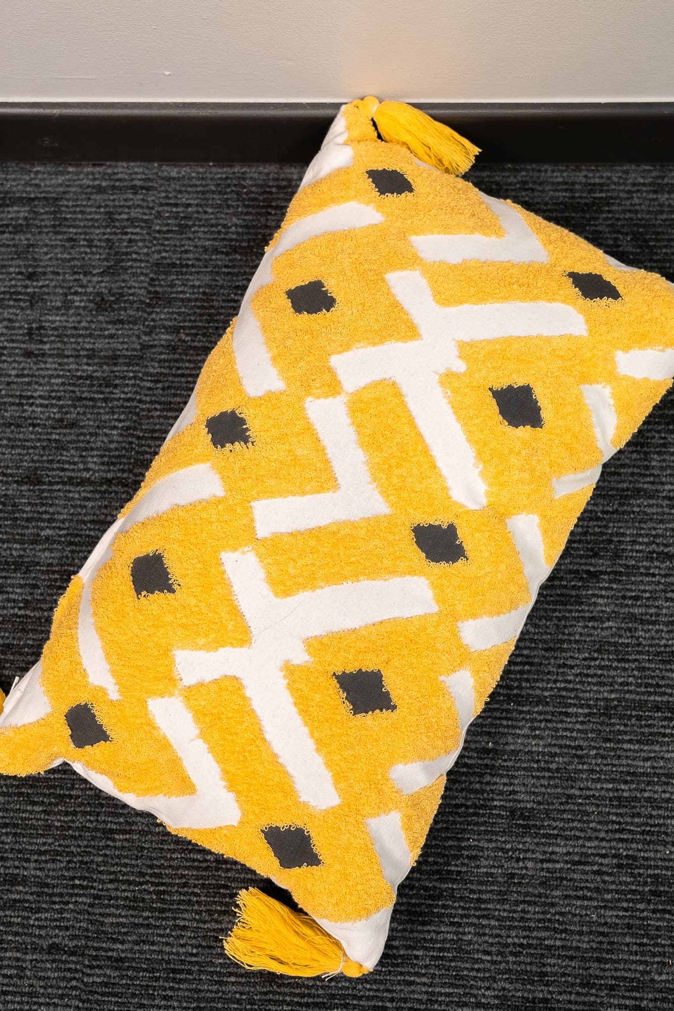 white rectangular cushion with yellow embroidery and tassels