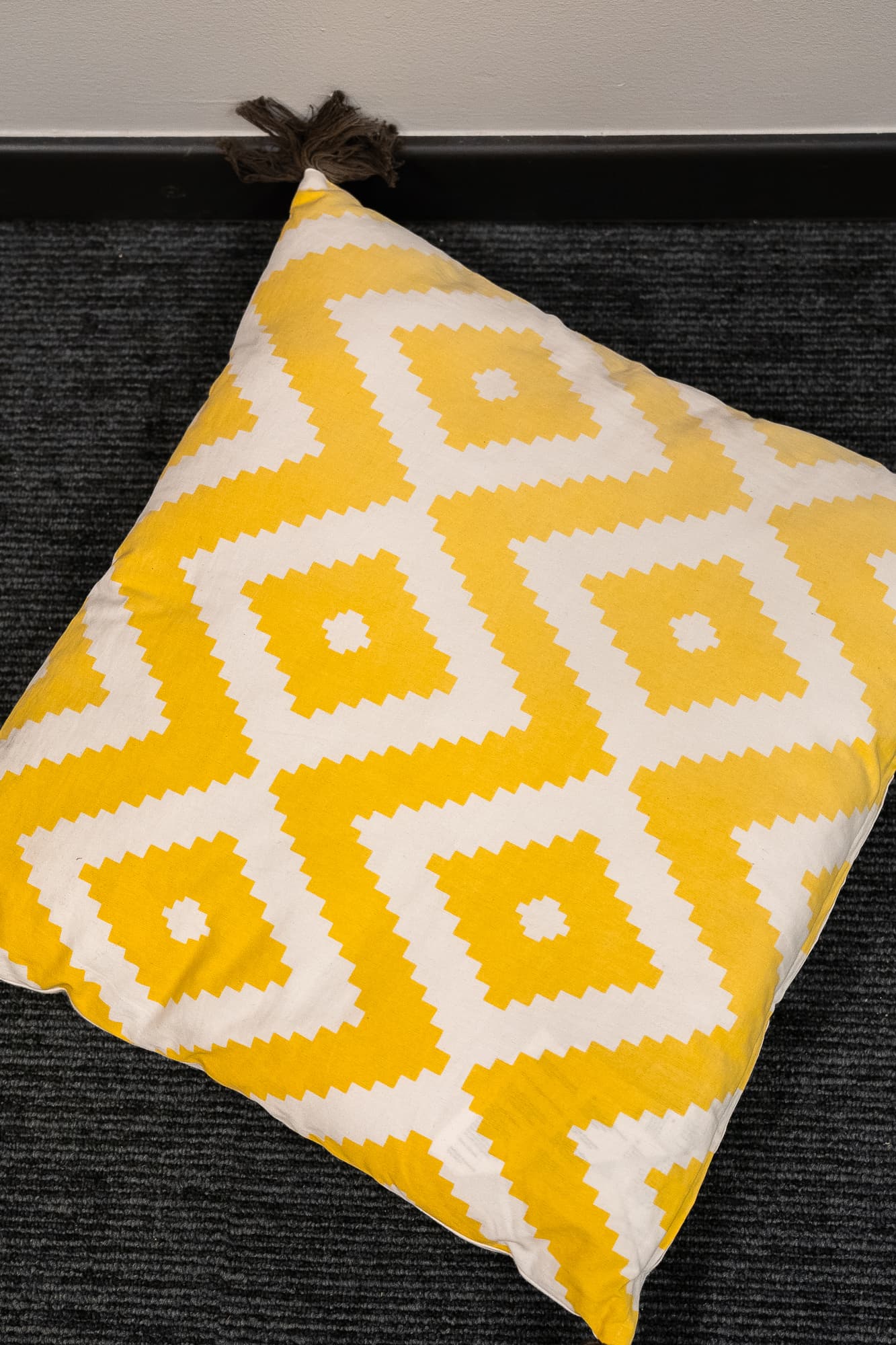 white cushion with yellow diamond pattern and tassels